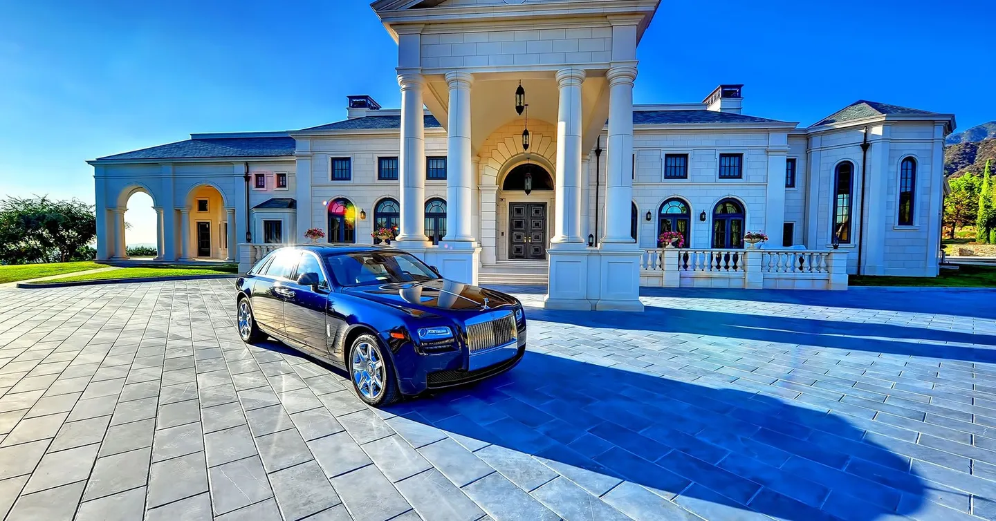 A luxurious car parked outside the mansion